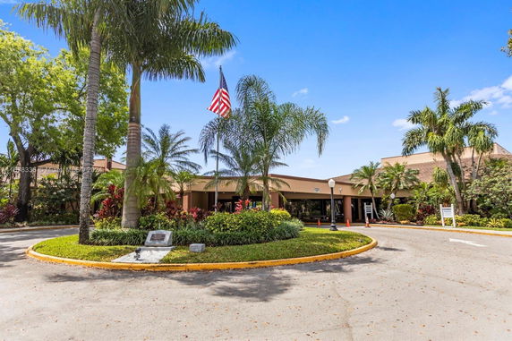 Front view of a building with palm trees and an American flag.