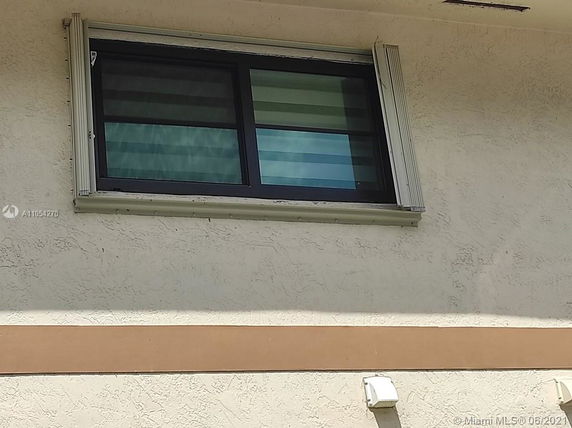 Exterior view of a building window with a beige stucco wall.
