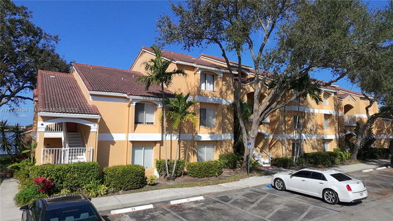 Front view of a multi-story residential building with a tiled roof and surrounding landscaping.
