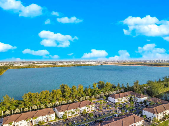 Panoramic view of residential area with buildings near a large water body and distant cityscape.