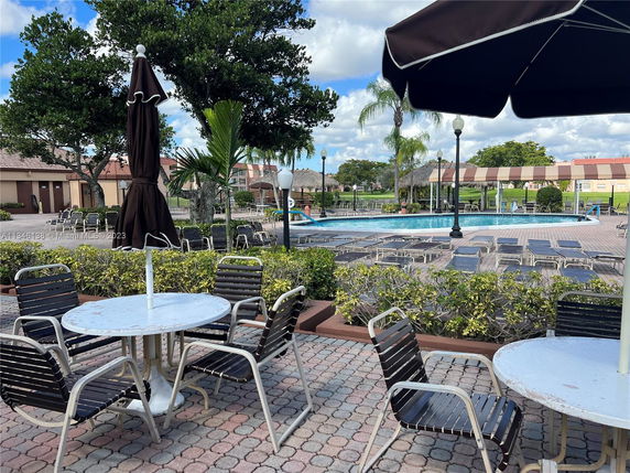 Outdoor pool area with lounge chairs and umbrellas.