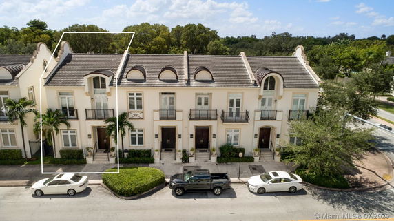 Front view of a two-story townhouse with a classic design and three entrances, each with a small balcony.