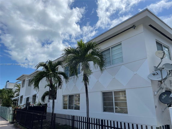 Front view of a two-story white building with decorative patterns and satellite dishes.