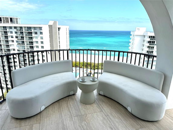 Panoramic view from a balcony with ocean and nearby buildings visible.