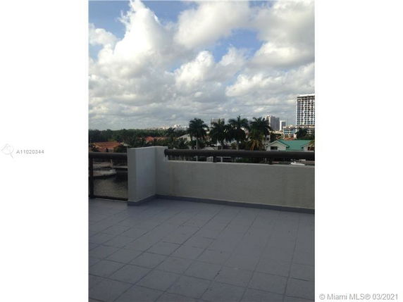 Rooftop terrace with surrounding view of city buildings and trees.
