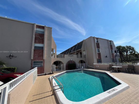 Outdoor view of a building complex with a swimming pool in front.
