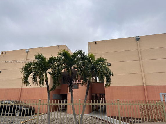 Front view of a multi-story commercial building with palm trees in front.