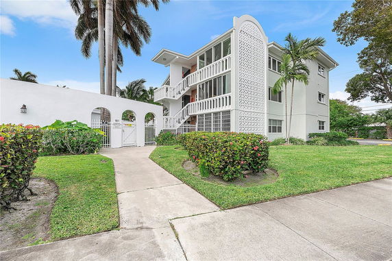 Front view of a multi-story building with a decorative facade and surrounding green lawn.