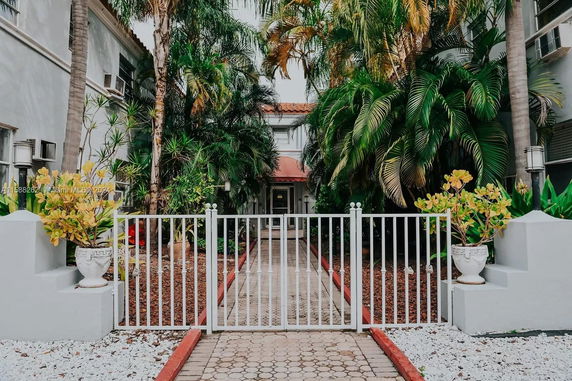 Front view of a house with a gated entrance and lush greenery.