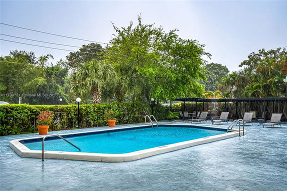 Outdoor swimming pool with surrounding greenery and lounge chairs.