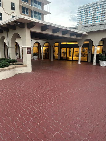 Entrance view of a multi-story building with arches and columns.