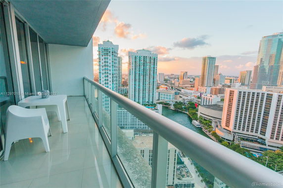 View from a high-rise balcony overlooking a cityscape with tall buildings and a river.