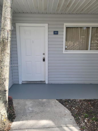 Front view of a house entrance with a closed white door and window.