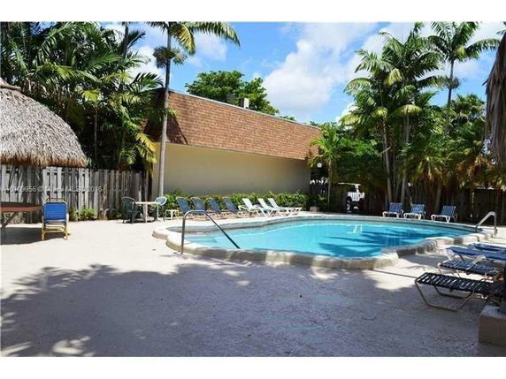 Outdoor swimming pool area with lounge chairs and tropical plants.