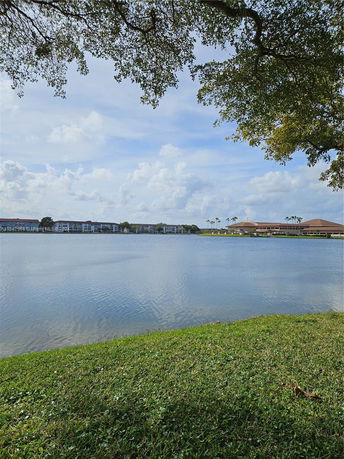 View of a lake with buildings in the background under a partly cloudy sky.
