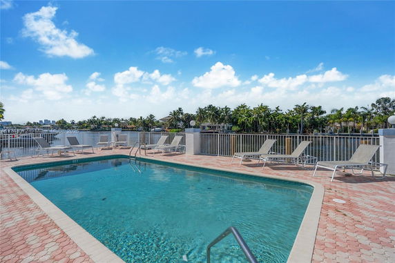 Outdoor swimming pool area with lounge chairs and view of surrounding water and trees.