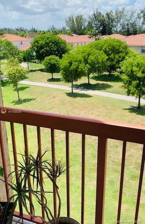 View from a balcony showing trees and rooftops in the background.