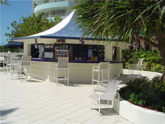 Outdoor seating area with a round bar and chairs.