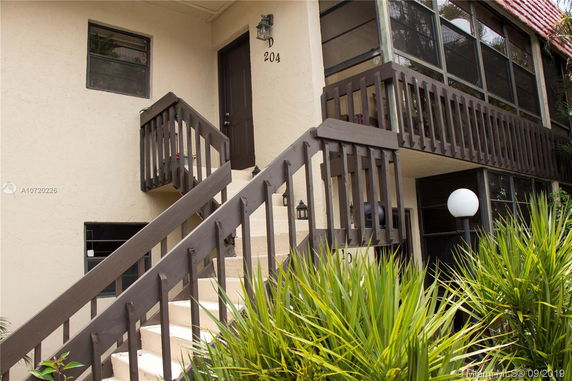 Exterior facade of a two-story building with stairs leading to the upper level and balcony railings.