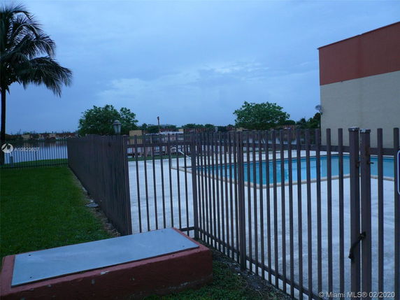 Outdoor swimming pool surrounded by a metal fence.
