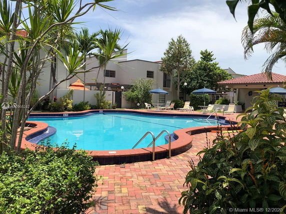Outdoor swimming pool with surrounding seating and umbrellas.