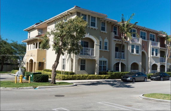 Front view of a multi-story residential building with arched balconies and a tiled roof.