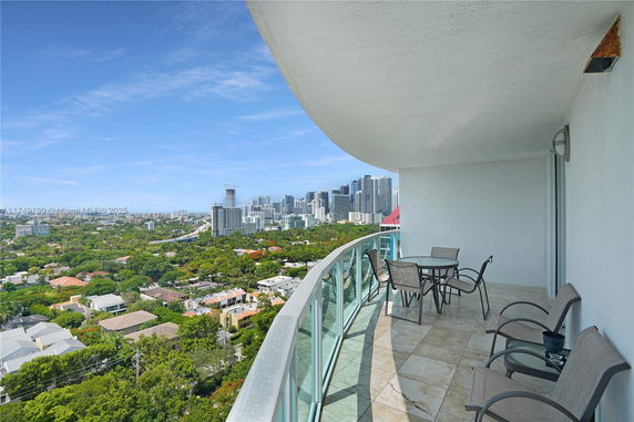 Wide-angle view of a city skyline from a high-rise building balcony with seating area.