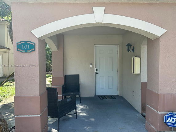 Front view of a house entryway with arch design and patio seating.