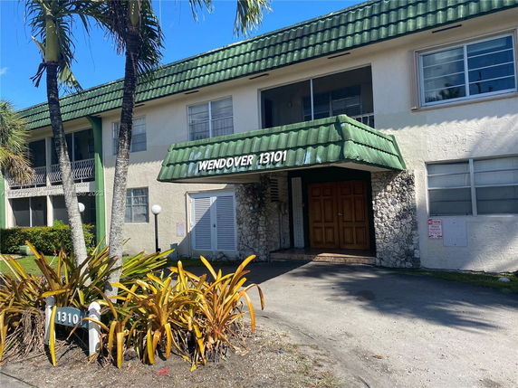 Front view of a two-story building with a green tiled roof and stone façade entrance.