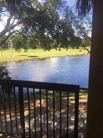 View of waterway and grassy area with trees from a balcony.