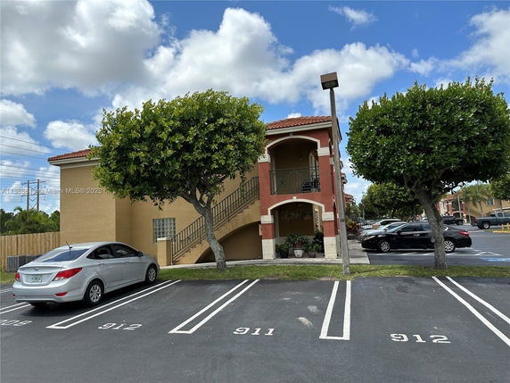 View of a parking area with a two-story building in the background.