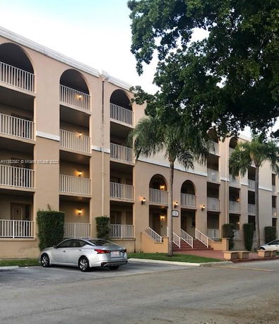Front view of a multi-story residential building with balconies and arched entrances.