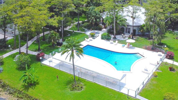 Aerial view of a swimming pool surrounded by greenery and trees.