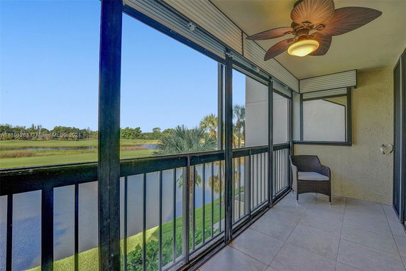 Balcony view of surrounding areas with a large ceiling fan and outdoor seating.