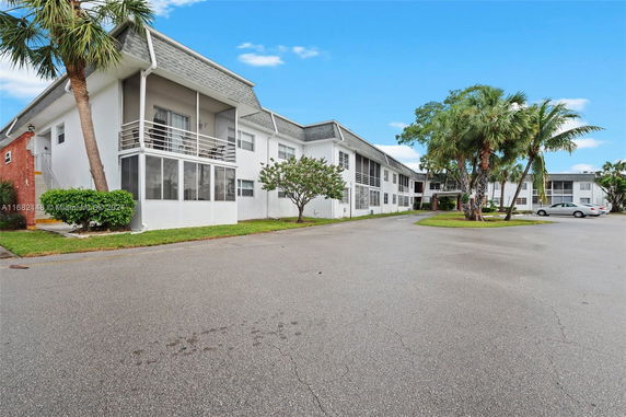 Front view of a two-story apartment building with balconies and a parking area.