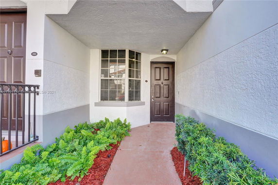 Front view of a house entrance with a brown door and a bay window.