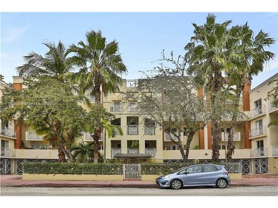 Front view of a multi-story residential building with balconies and surrounded by trees.