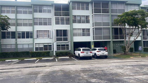 Front view of a multi-story building with large windows and parking space.