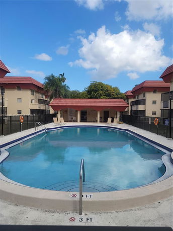 View of an outdoor swimming pool surrounded by residential buildings with red roofs.