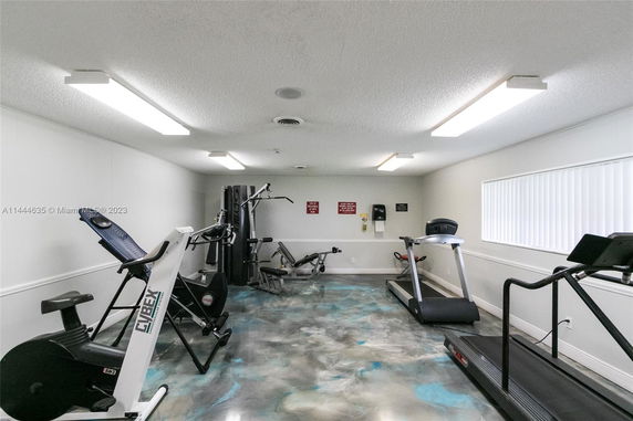 Interior view of a gym room with exercise equipment, including treadmills and weights.