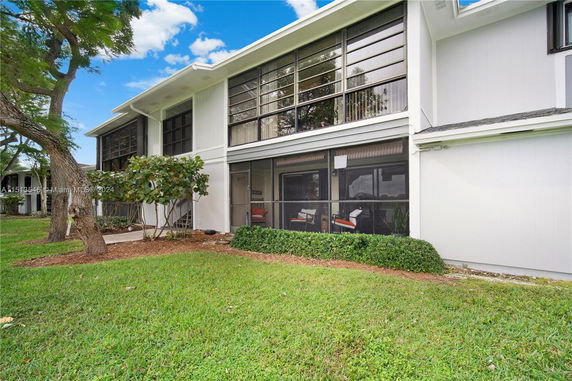 Front view of a two-story house with large windows and a screened patio.