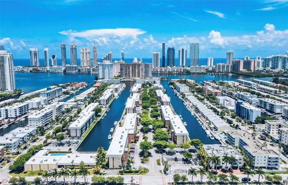 Arial view of residential area with water canal and city skyline in the background.
