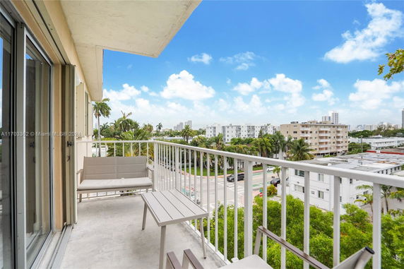 Balcony view overlooking a neighborhood with nearby buildings and palm trees.