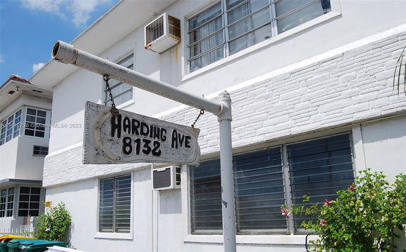 Front view of a two-story white building with multiple windows and a sign reading 'Harding Ave 8132.'