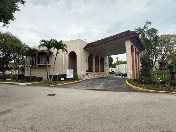 Front view of a building with an arched entryway and covered driveway.