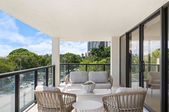 Balcony view with outdoor seating overlooking trees and buildings.