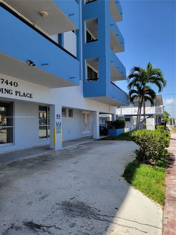 Outdoor parking area outside a multi-story blue building.