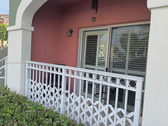 Front view of a house with an arched entrance and white railing.