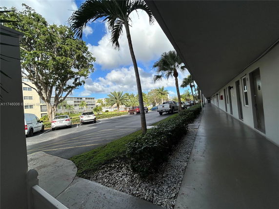 Outdoor parking area with several parked cars near a building.