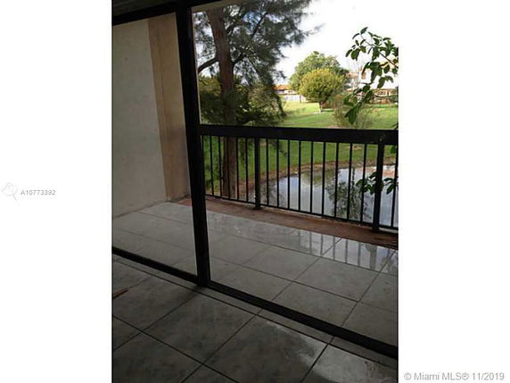 View from a balcony overlooking grassy area and trees.